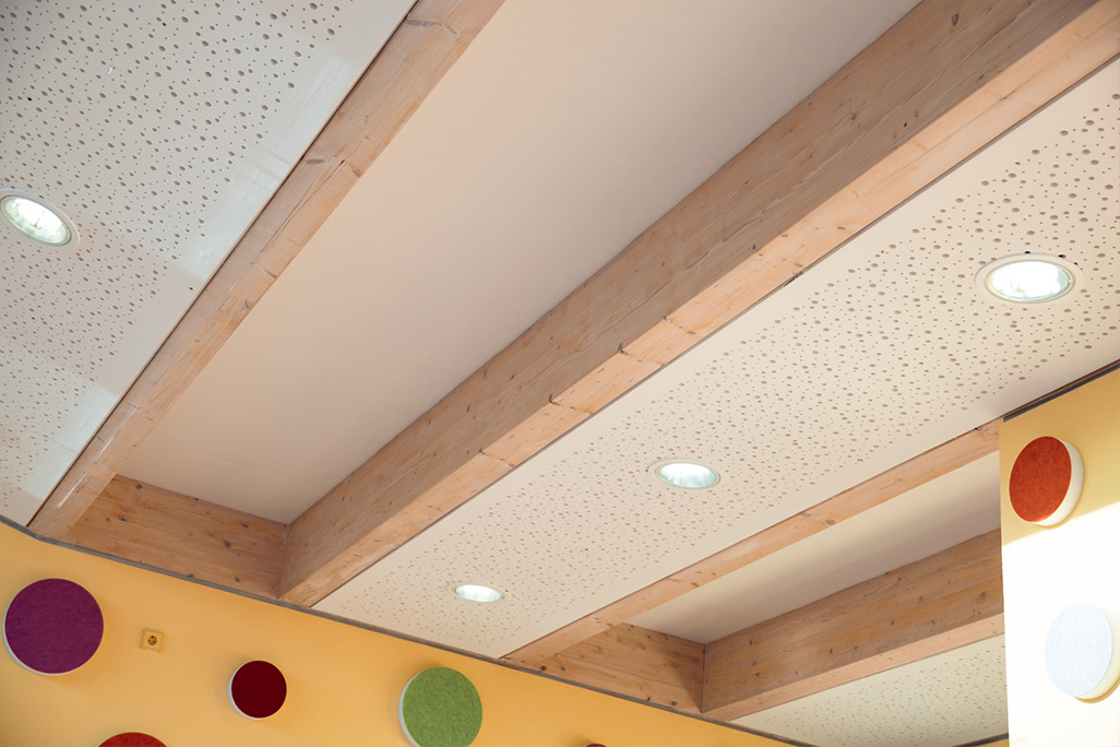 Deckenbalken aus Holz mit weißen Vliesplatten dazwischen