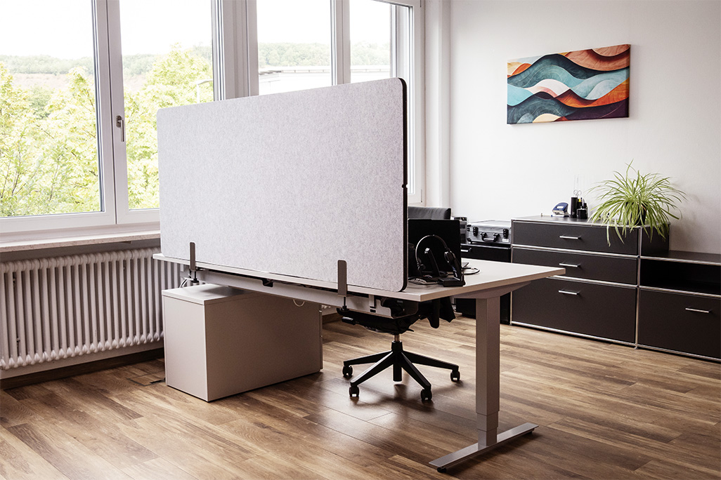 Hellgraue Tischtrennwand in einem Büro auf dem Schreibtisch montiert
