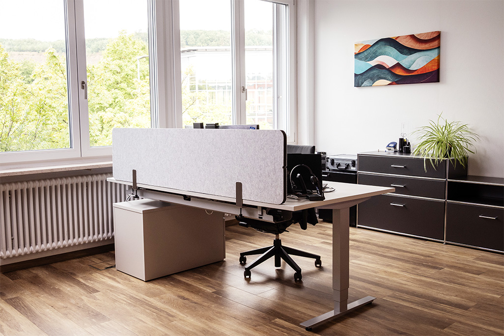 Hellgraue Tischtrennwand in einem Büro auf dem Schreibtisch montiert