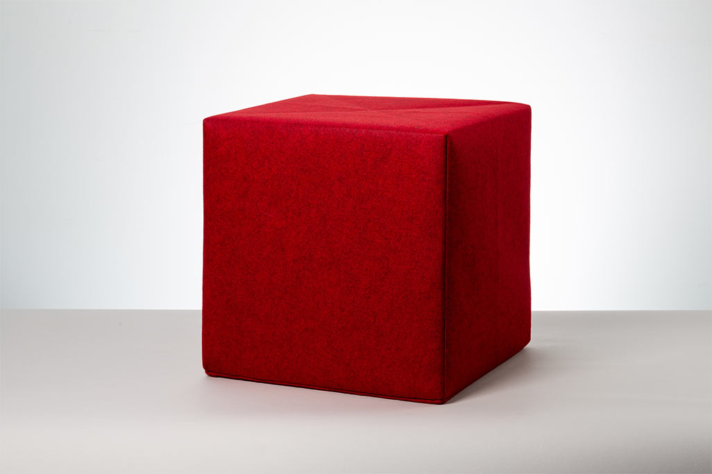 Roter Sitzwürfel vor weißem Hintergrund fotografiert.