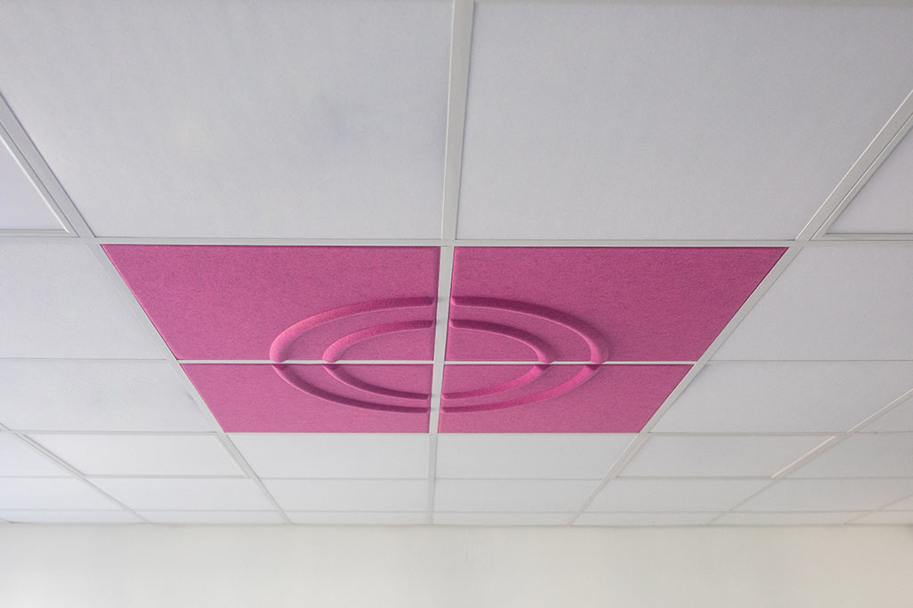 Ausschnitt einer handelsüblichen Rasterdecke mit eingelegten Akustikabsorbern soni COMFORT SD in Weiß und soni COLOR Design in Pink.