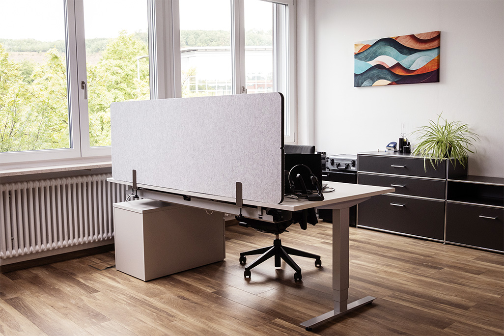 Hellgraue Tischtrennwand in einem Büro auf dem Schreibtisch montiert