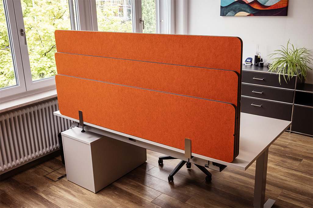 Orangene Tischtrennwand in einem Büro auf dem Schreibtisch montiert